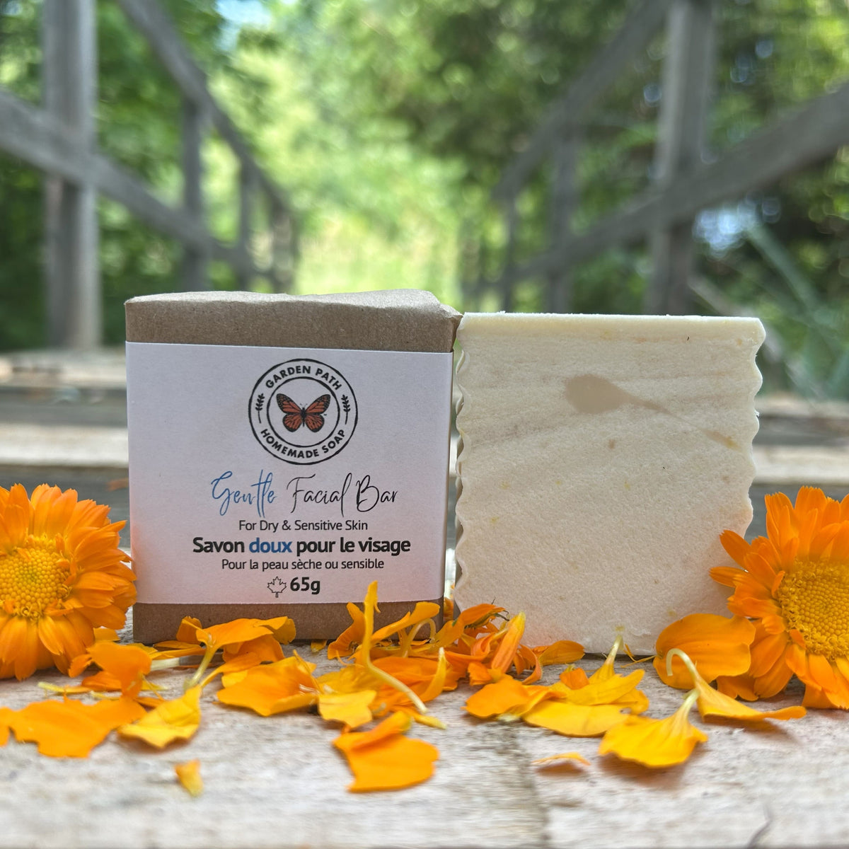 Gentle Facial Bar of soap (both wrapped and unwrapped) with calendula petals on a wooden surface by Garden Path Homemade Soap. for dry, sensitive skin | 100% Natural Ingredients
