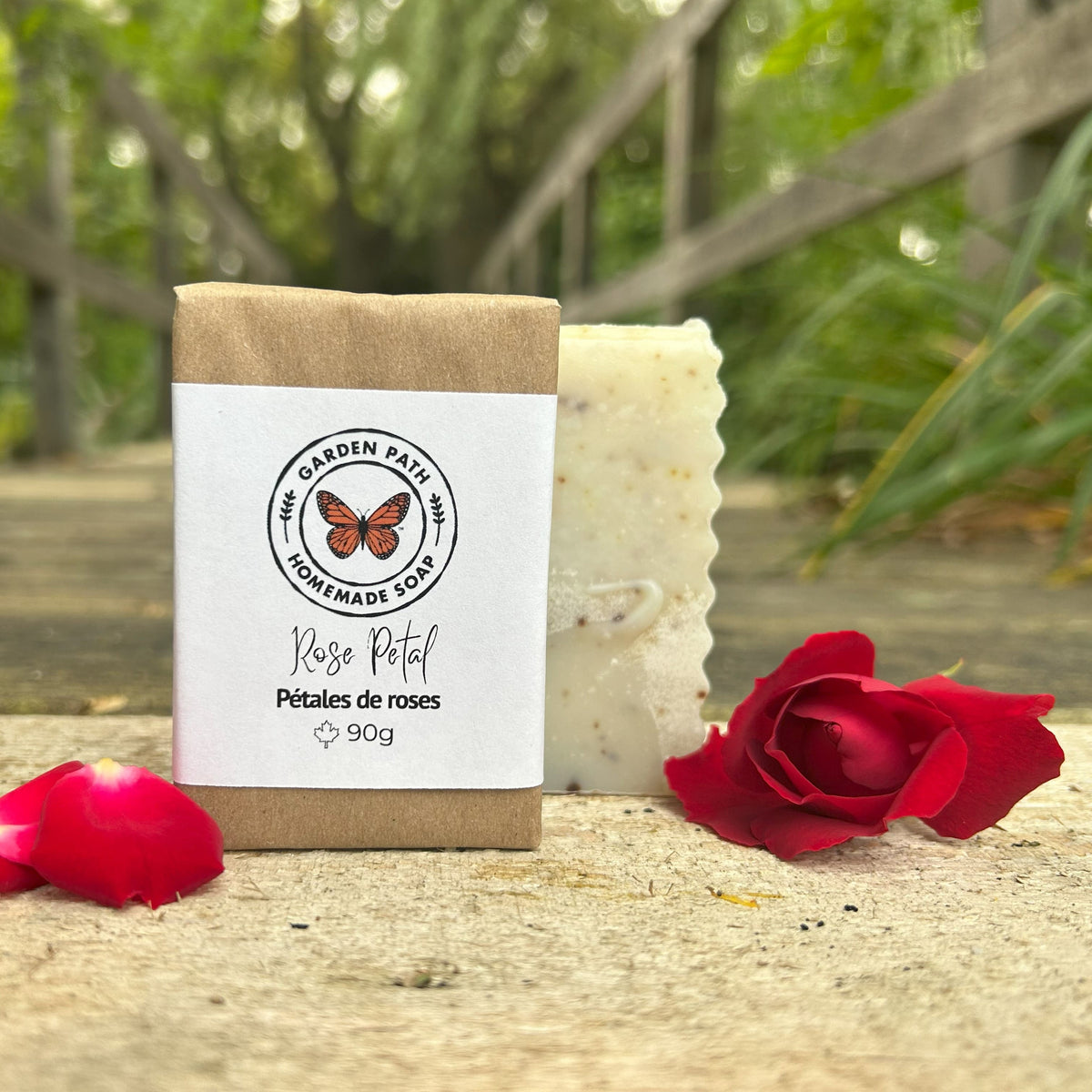 Rose Petal bar of soap with a 'Garden Path Homemade Soap' label, surrounded by red roses on a natural surface. Lightly Scented Fragrance