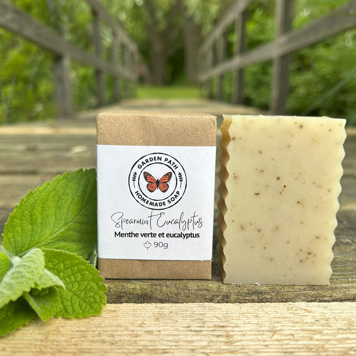 Spearmint Eucalyptus Bar Soap on a wooden surface with mint leaves beside the wrapped and unwrapped bars. | 100% Natural Essential Oils & Ingredients - Garden Path Homemade Soap