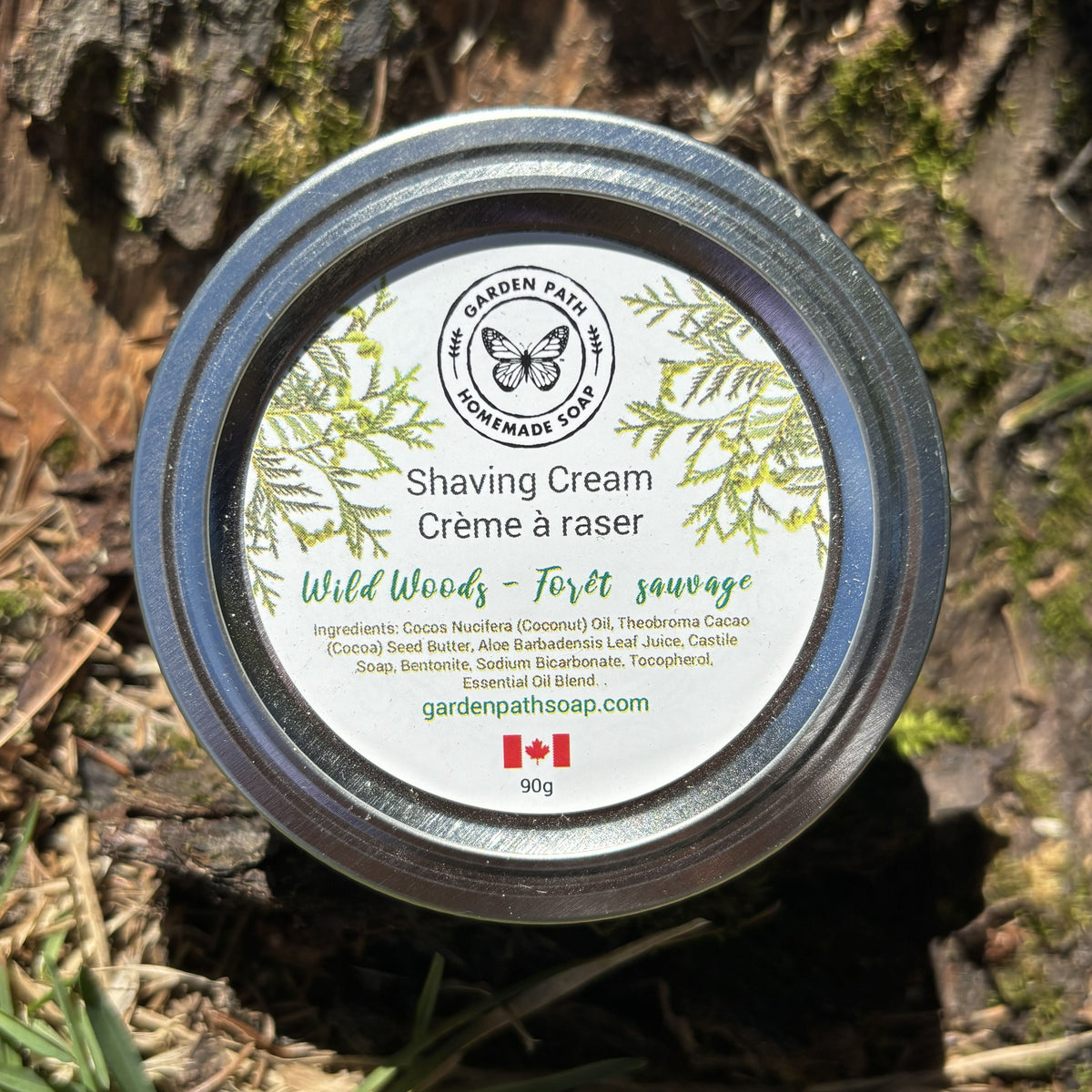 Shaving cream container labeled 'Wild Woods' on a natural background by Garden Path Homemade Soap