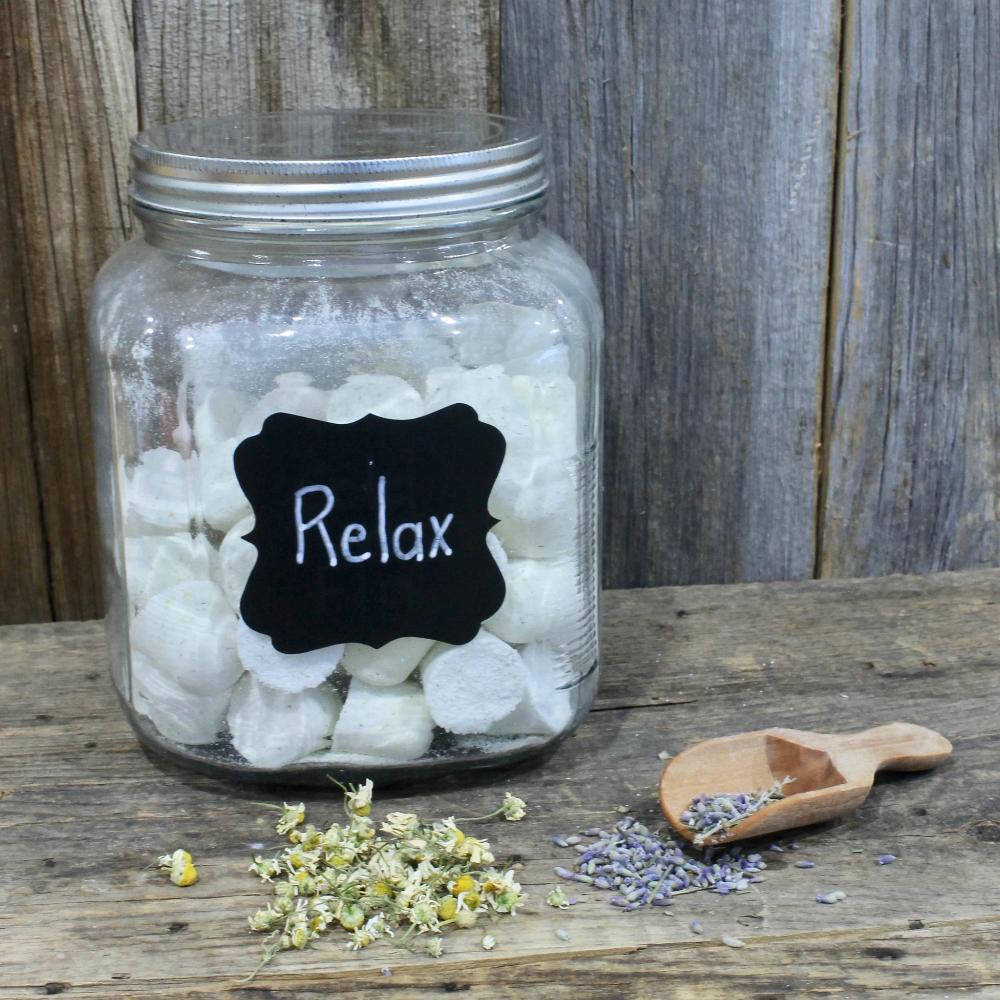 Jars filled with Relax shower tablets, with ingredients like dried lavender and chamomile on the wooden surface by Garden Path Homemade Soap. 100% Natural Essential Oils | Aromatherapy